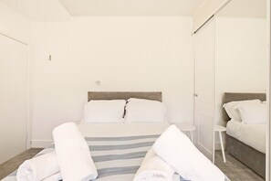 A hotel room with a bed, a bedside table, a mirror, and a wardrobe. - Sunset Views - North East Escapes (Tynemouth)