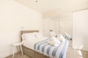 Une chambre d’hôtel avec un lit, une petite table de chevet, un miroir et une armoire.