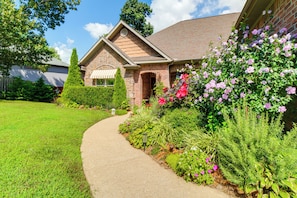 A house with a brick exterior, a stone chimney, and a pathway leading to the front door.