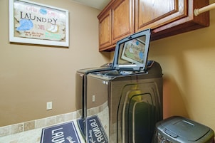 A compact kitchen with a built-in washer and dryer, a wooden cabinet above, and a laundry sign on the wall.