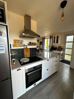 Una cocina moderna con una isla central, horno empotrado y electrodomésticos de acero inoxidable.