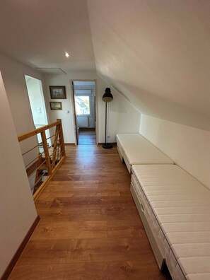 A narrow hallway with wooden flooring leading to a bedroom with a bed and a floor lamp. - Family home in Camaret-sur-Mer, with beaches within walking or biking distance. (Camaret-sur-Mer)