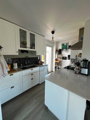 A modern kitchen with white cabinetry, a large island, and a view of the outdoors. - Family home in Camaret-sur-Mer, with beaches within walking or biking distance. (Camaret-sur-Mer)