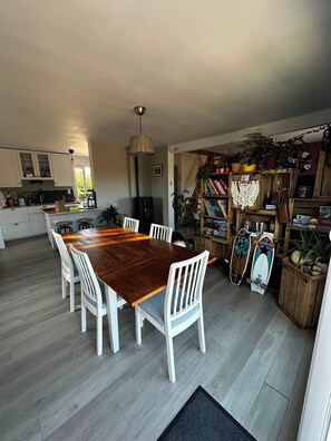 A modern kitchen with white cabinetry, a wooden dining table, and a variety of plants and books. - Family home in Camaret-sur-Mer, with beaches within walking or biking distance. (Camaret-sur-Mer)