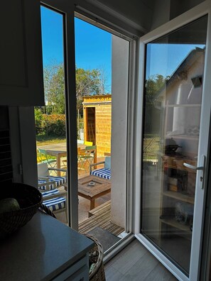 A room with a sliding glass door leading to an outdoor area with a wooden structure and outdoor furniture. - Family home in Camaret-sur-Mer, with beaches within walking or biking distance. (Camaret-sur-Mer)