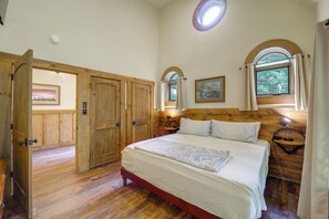 A bedroom with a large bed, wooden wardrobe, and a window with a view of greenery. - Outdoor Kitchen! 'the Hobbit House' on Elk River (Elk Park)