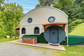 Ein kleines, eingeschossiges Gebäude mit einer gewölbten Dachform, einer großen Zwerchhaustür und zwei kleineren Fenstern.