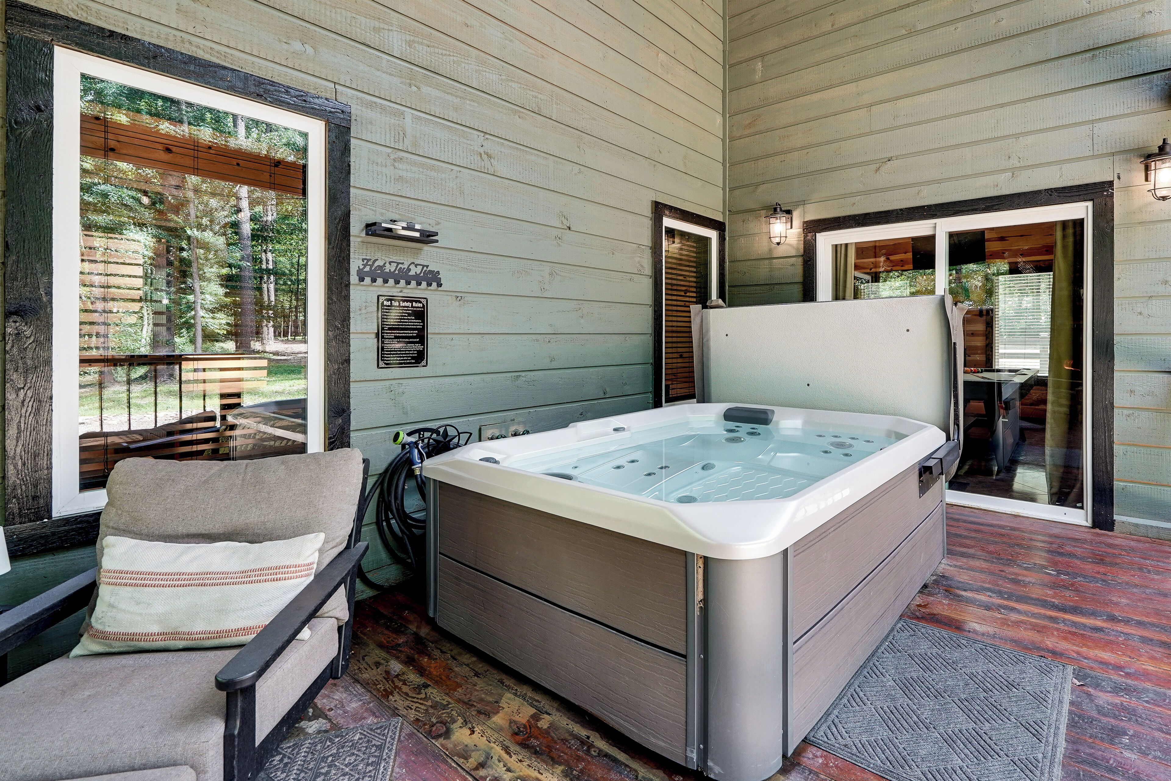 A hot tub in a wooden cabin with a chair and a safety sign.