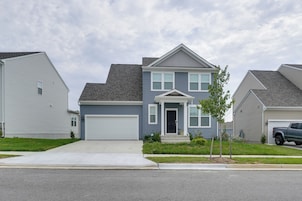 A two-story residential house with a front garage, a small front yard, and a street view.