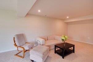 A room with a wooden chair, a sofa, and a small table with a vase of flowers.