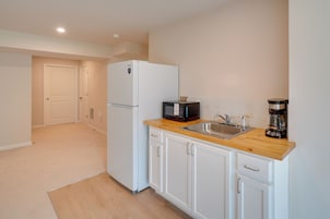 A compact kitchen with white cabinetry, a built-in microwave, and a coffee maker on the countertop.