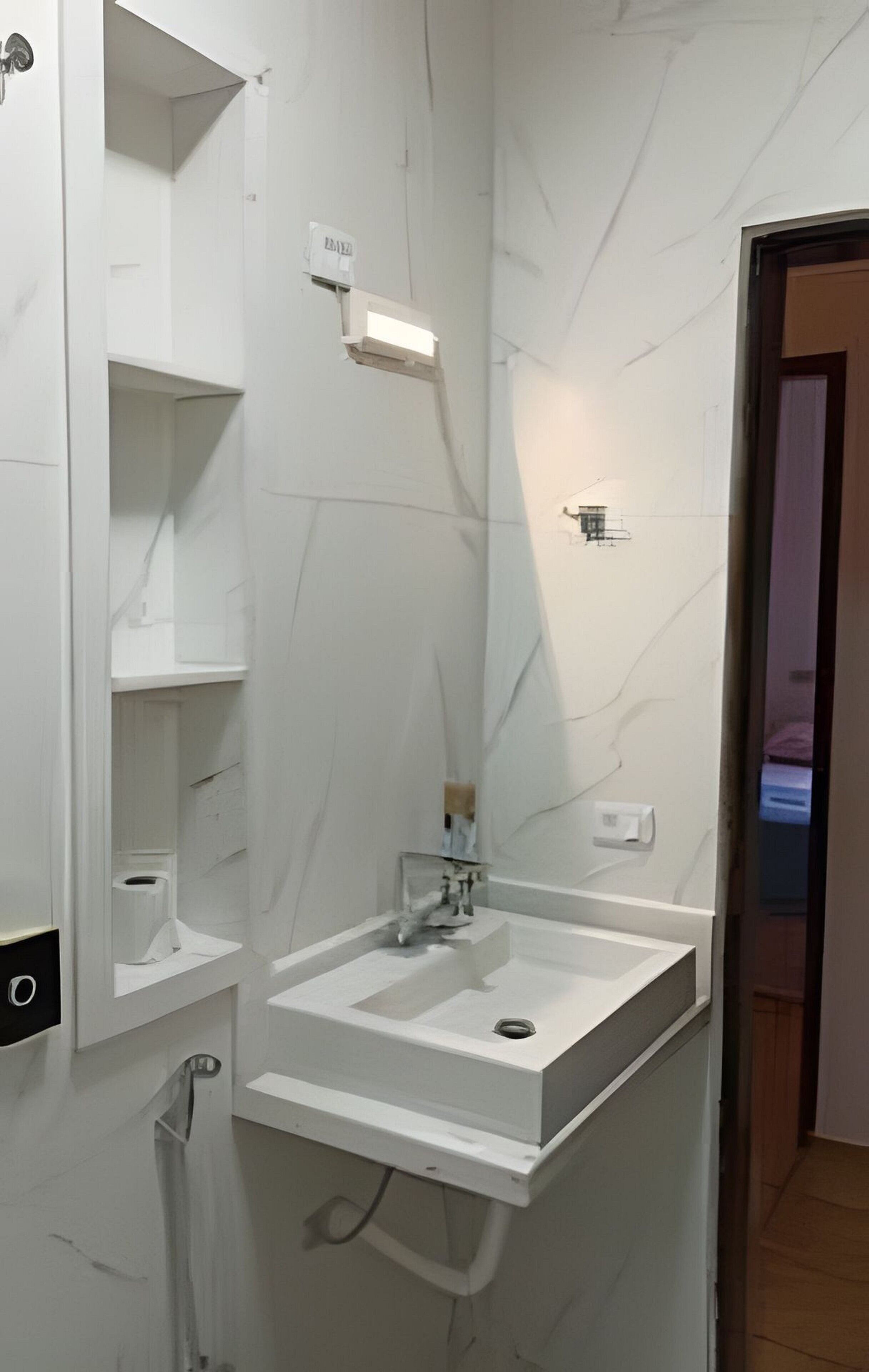 Un baño con lavamanos blanco, un espejo y un perchero para toallas.