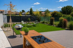 A backyard with a wooden deck, a barbecue grill, and a small table with a potted plant. - L'Aure Mar; Sunny villa 5 minutes from the beach (Saint-Cyprien)