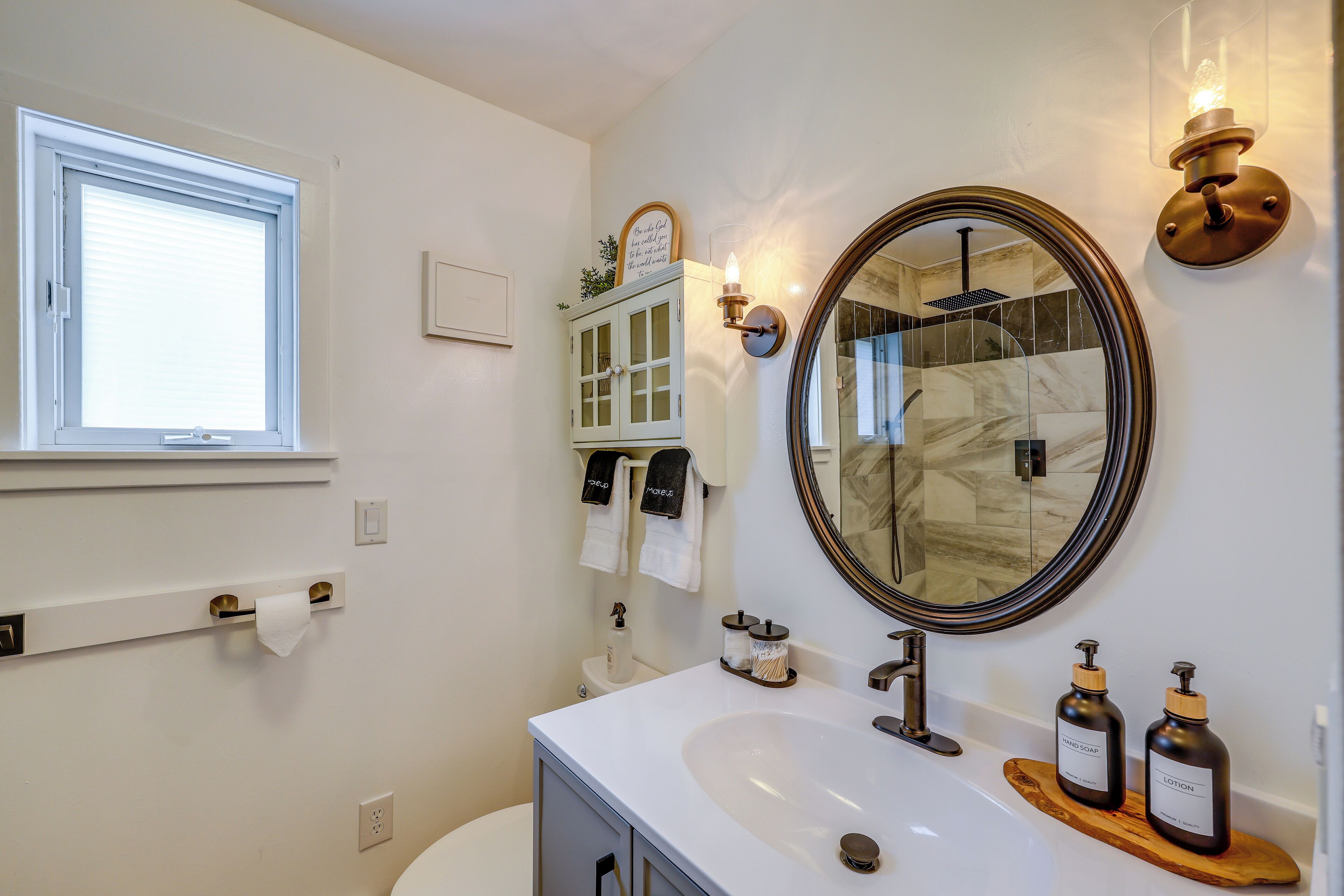 A bathroom with a white sink, a mirror, a towel rack, and a window.