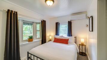 A neatly arranged bedroom with a bed, bedside lamps, a window with curtains, and a ceiling light fixture.