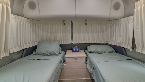 Ein kleines Zimmer mit zwei Betten, einem Tisch und einem Deckenventilator.