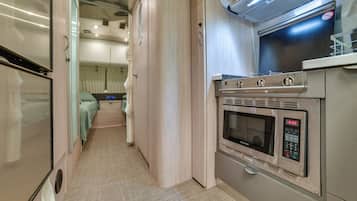 A compact kitchen with a microwave, oven, and a small countertop.
