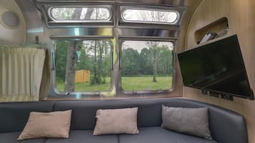 A cozy interior with a sofa, three windows, and a flat-screen TV.