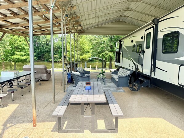 An RV with a covered patio area, including a picnic table and outdoor seating.
