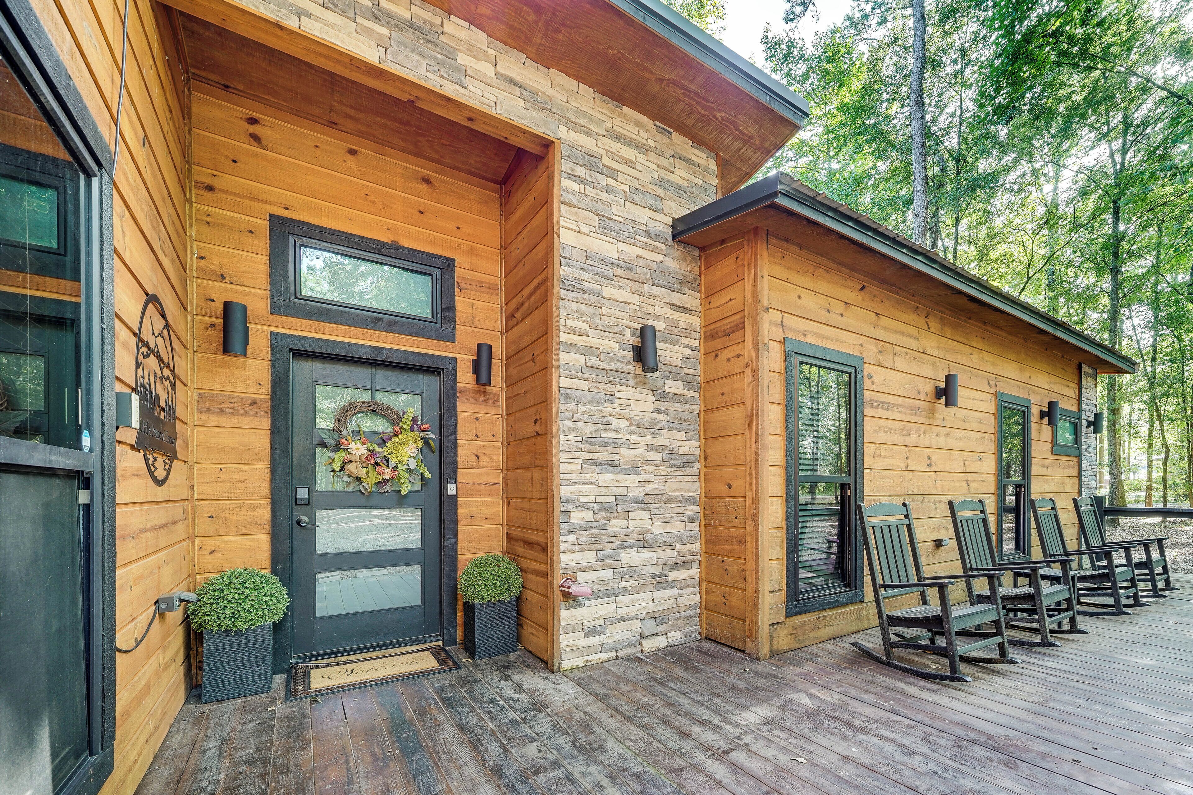 Een houten chalet met een gevel van steen, een voordeur met een krans, en een terras met stoelen.