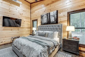A wooden-paneled bedroom with a bed, nightstands, and a large window. - Hike, Soak & Play! Luxe Broken Bow Escape (Broken Bow)
