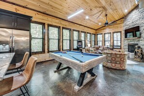 A spacious room with a pool table, seating area, and a stone fireplace. - Hike, Soak & Play! Luxe Broken Bow Escape (Broken Bow)