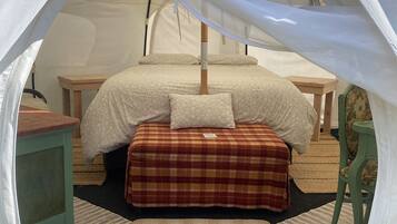Una carpa con una cama en su interior, que incluye un dosel, almohadas y una manta.