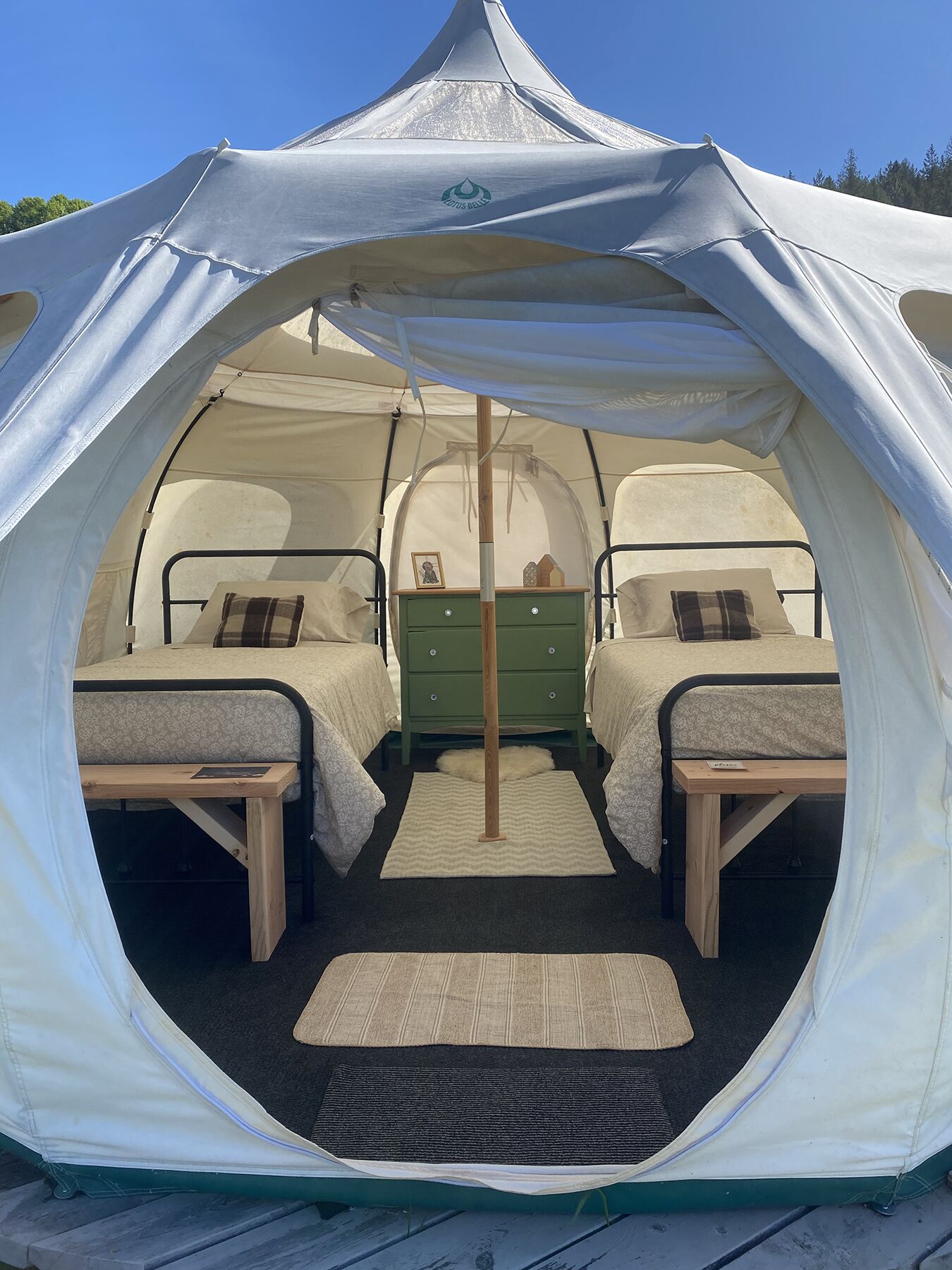 Une tente en forme de dôme, équipée de deux lits, d’une commode en bois et d’une petite table.