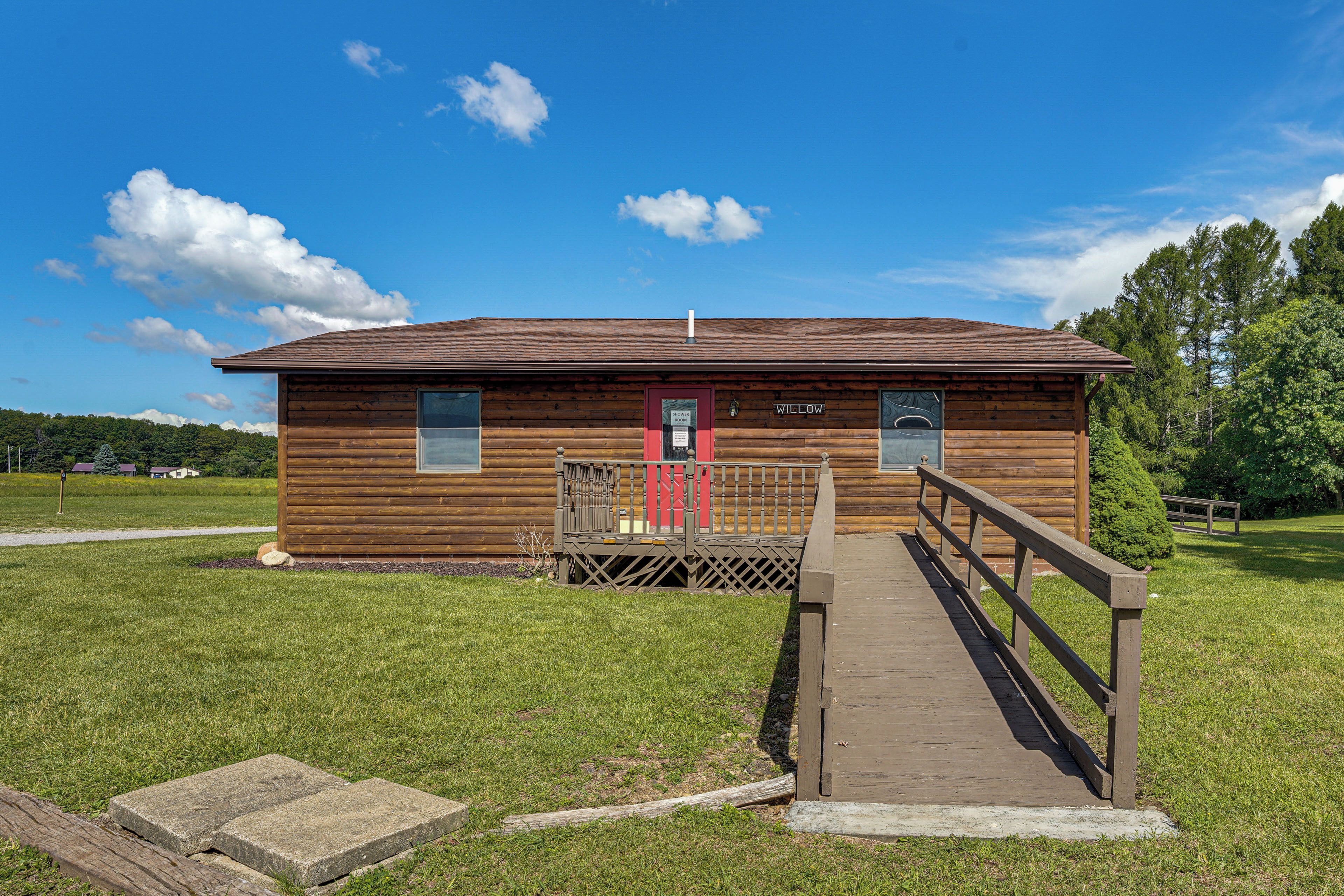 A wooden cabin with a red door, a wooden deck, and a sign indicating a shower room.