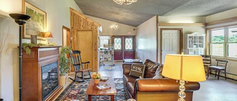 A cozy lobby with a fireplace, leather seating, a chandelier, and a bookshelf.