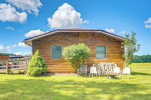 Une cabane en bois avec un toit en pente, deux fenêtres et une petite véranda comprenant une chaise et une table.