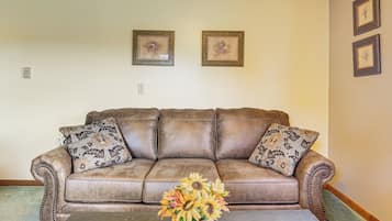 A brown leather sofa with patterned cushions, a coffee table, and a floral arrangement.