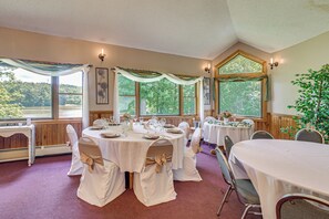 Un salón de banquetes con mesas redondas, manteles blancos y sillas con cintas color beige.