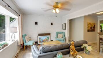 A living room with a sofa, a chair, a coffee table, and a ceiling fan.