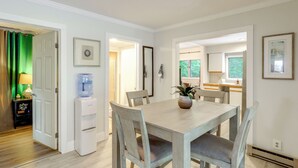 A dining area with a table, chairs, a water dispenser, and a potted plant. - Home With Water Access: Close to Saratoga (Ballston Lake)