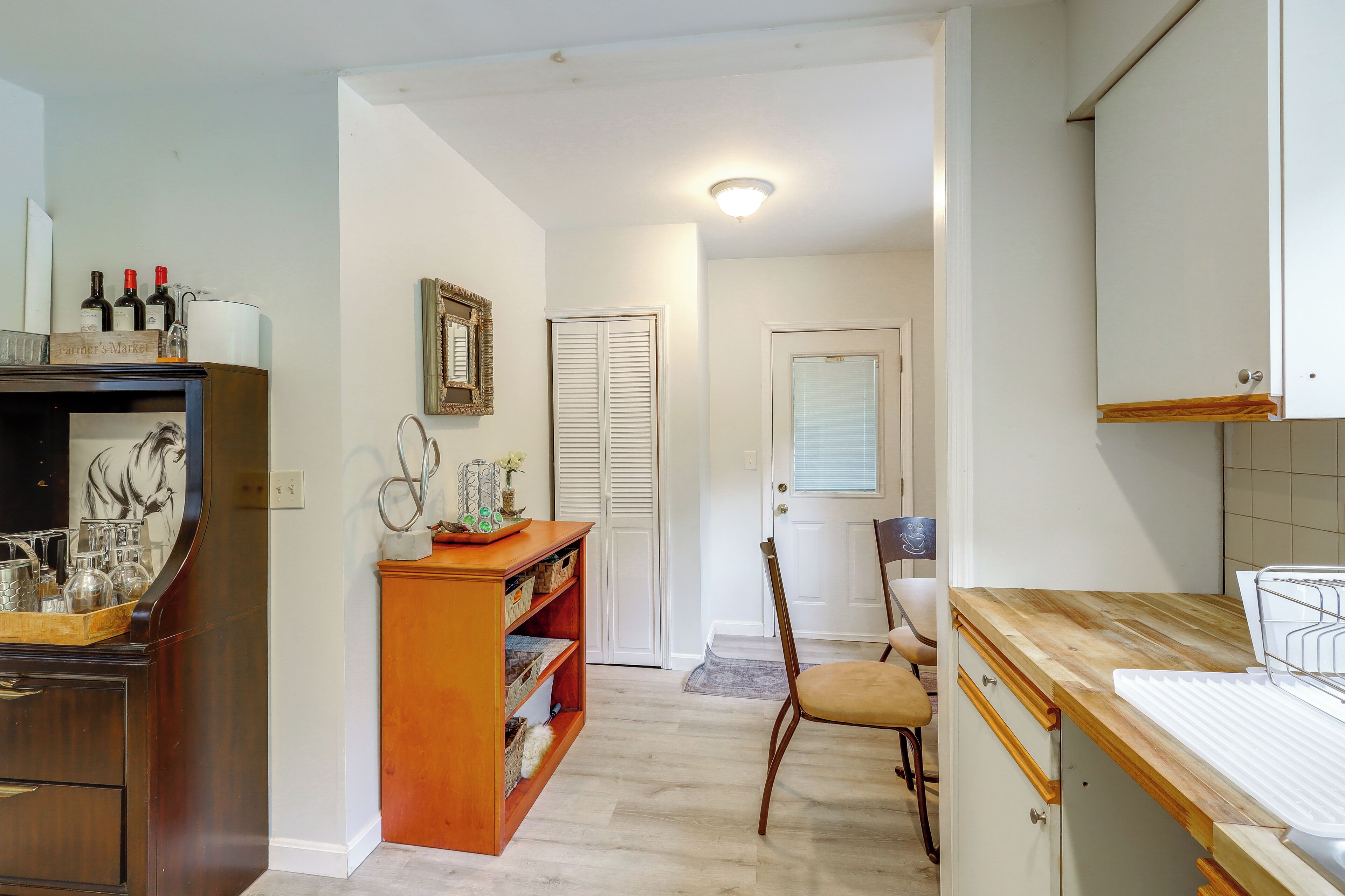 A kitchen with wooden cabinets, a countertop, and a dining area with a chair.