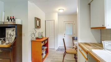 A kitchen with wooden cabinets, a countertop, and a dining area with a chair.