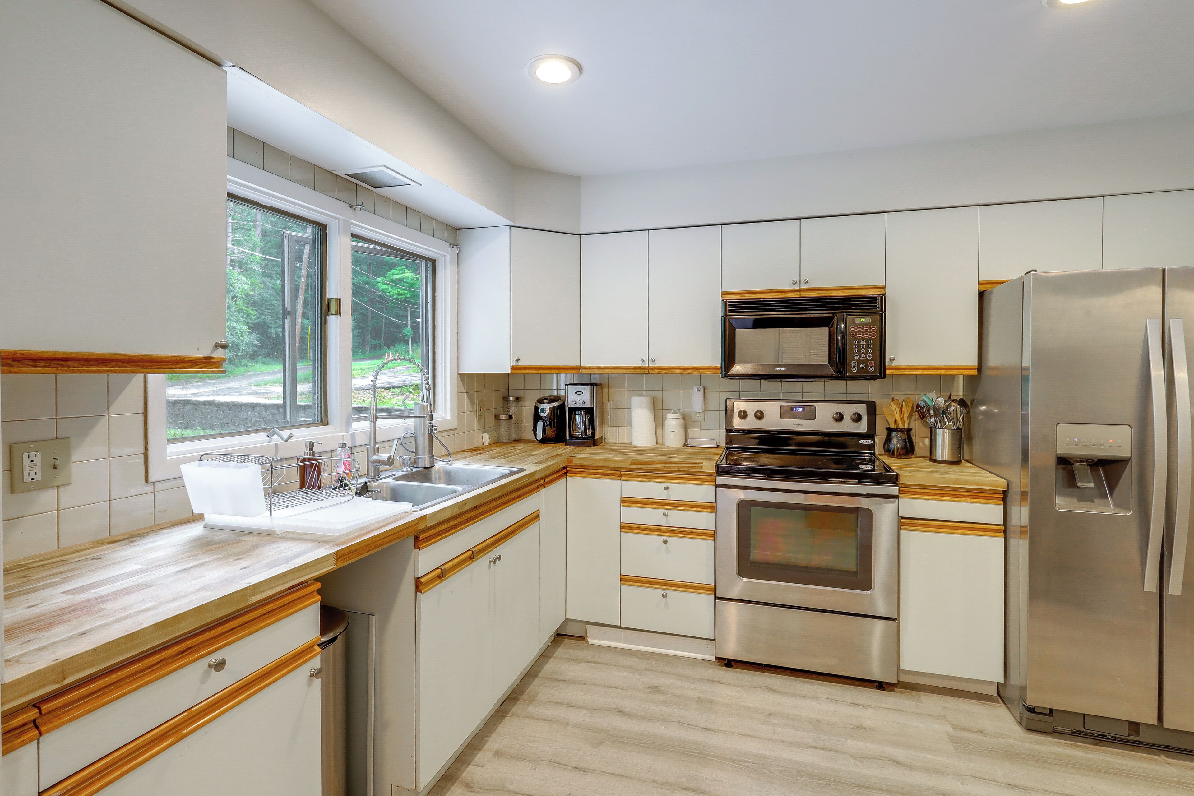 Een moderne keuken met roestvrijstalen apparatuur, houten aanrecht en een raam met uitzicht op de omgeving.