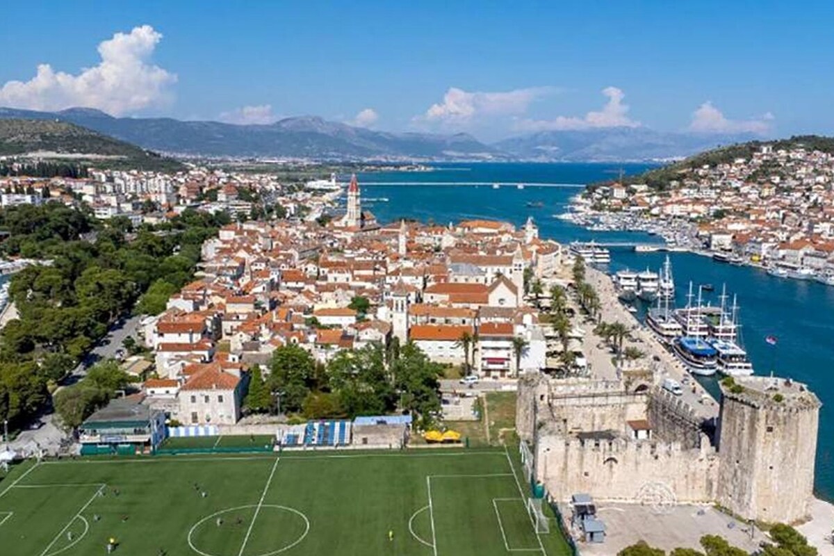 A coastal city with a prominent castle, a marina, and a soccer field.