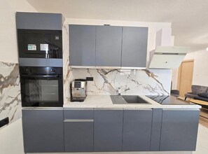 A modern kitchen with grey cabinets, a built-in oven, a coffee machine, and a marble backsplash. - Lux Adriatica Apartments (Okrug)
