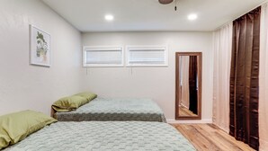 Un dormitorio con dos camas, una ventana, una puerta y una lámpara en el techo.