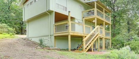Una casa de madera de dos pisos, con un balcón y una escalera que sube al nivel superior.