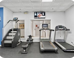 Exercise room featuring treadmills, a stair climber, a rower, and a wall-mounted TV. - Beach Days & Sunset Nights in Fort Lauderdale (Fort Lauderdale)