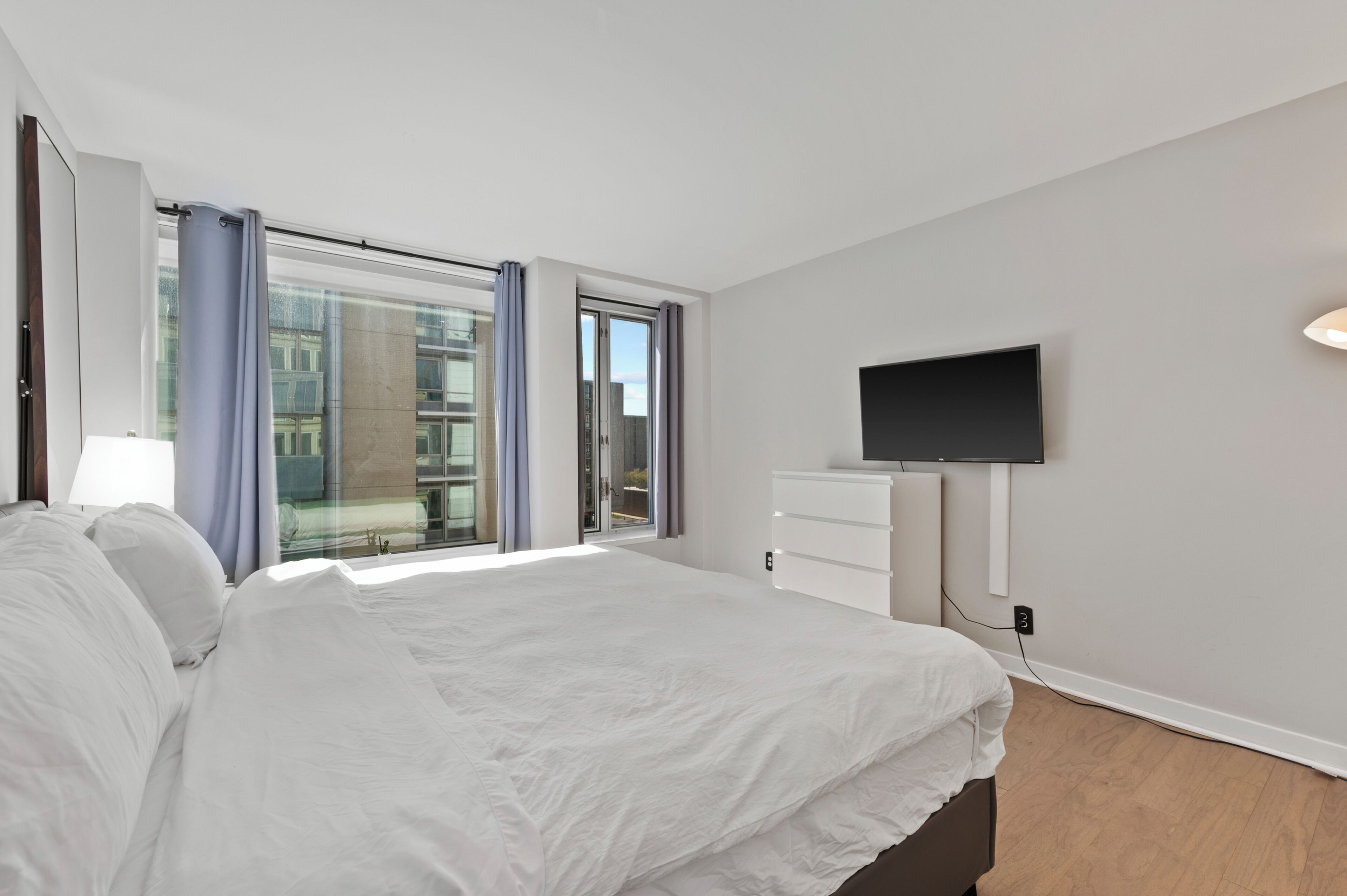 Una camera d'albergo moderna con un letto grande, una TV a schermo piatto montata a parete e una porta vetrata scorrevole che dà su un balcone.