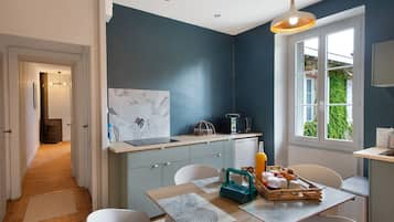 Una cocina moderna con pared azul oscuro, una mesa de comedor de madera con individuales, un microondas y un refrigerador.