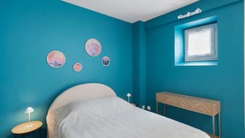 Een slaapkamer met een bed, nachtkastje, raam en wanddecoratie.