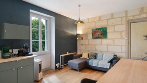Ein kompakter Wohnbereich mit Küchenzeile, Essbereich und einer Sitzecke mit Sofa und Hocker.