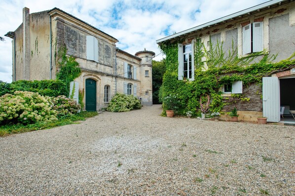 A gravel courtyard with two historic buildings, one with a green door and the other with ivy-covered walls. - Guest Room "L’annexe De Camillac - Room 2020" with Private Garden and Wi-Fi (Bourg)