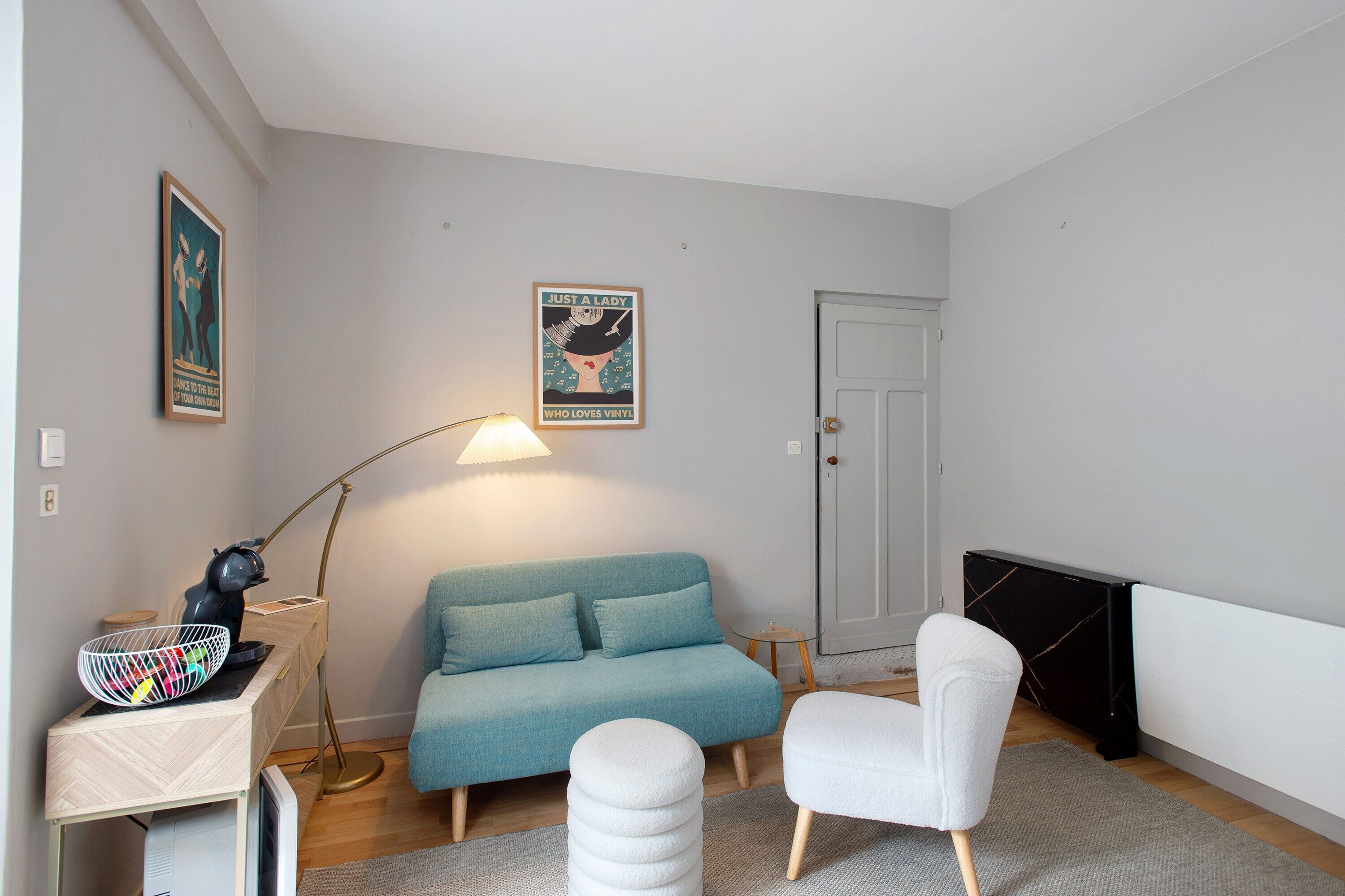 A modern living room with a sofa, a chair, a lamp, and a poster on the wall.