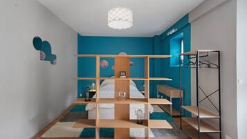 A bedroom with a bunk bed, a desk, a hanging light fixture, and a wardrobe.